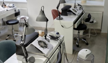 Shot of manicurist workplace equipped with nail tech desks with dust collectors and table lamps. White clean interior of empty beauty salon